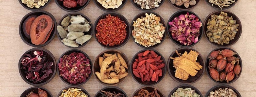 An assortment of traditional Chinese herbs is displayed in small wooden bowls