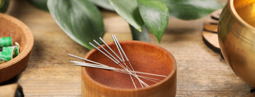 Bowl with acupuncture needles on wooden table